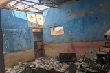 A classroom where the roof has collapsed and debris is spread across the room.
